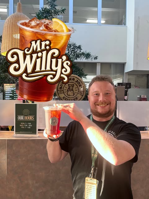 A student holding up a Mr. Willy's iced drink at the Brother Joe's counter