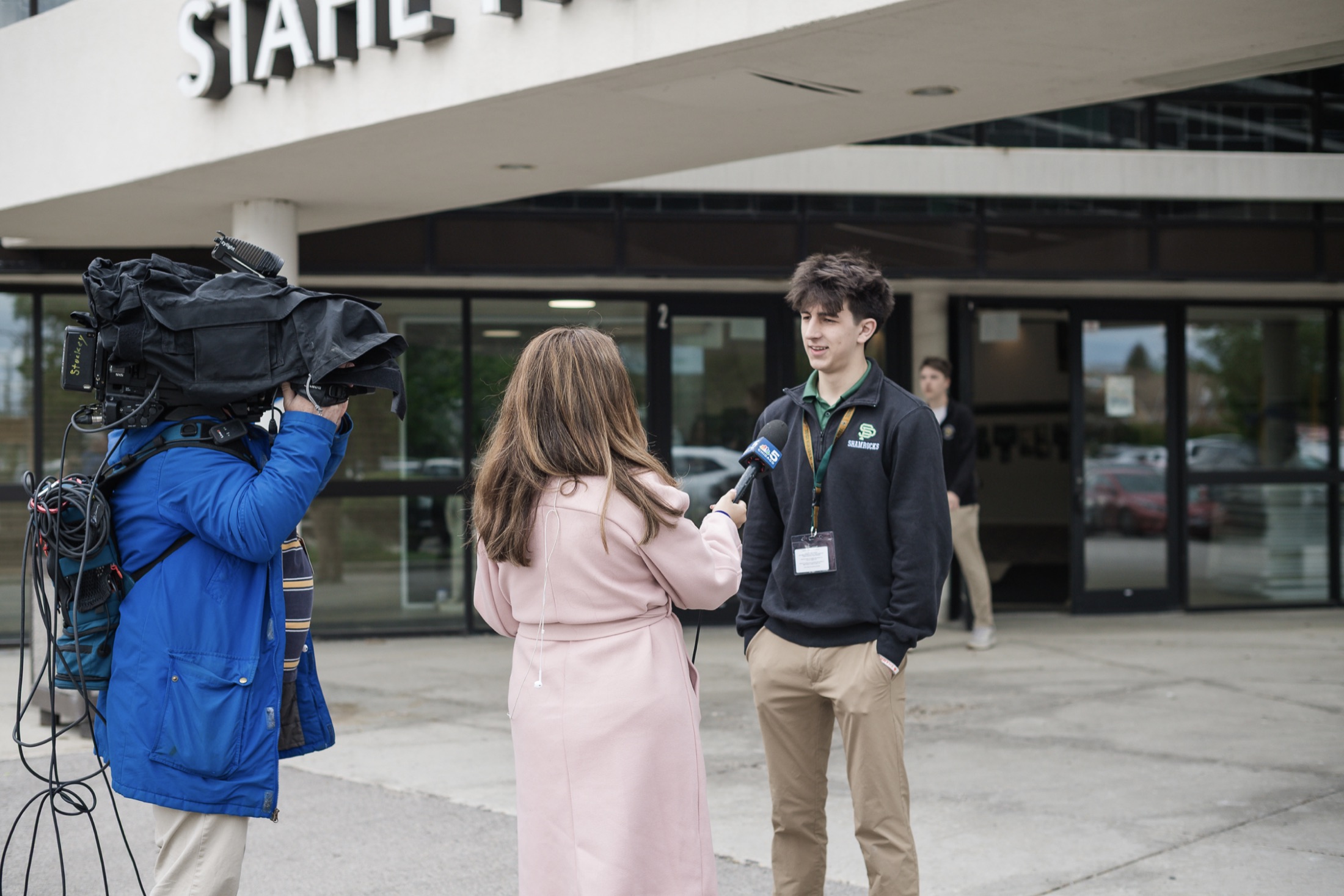 A Brother Joe's founder being interviewed by a TV news crew outside Saint Patrick High School